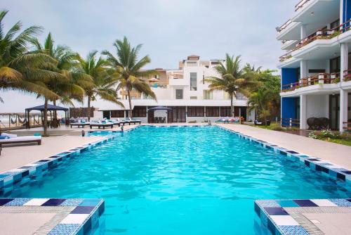 a swimming pool in front of a building with palm trees at Palmazul Hotel & Spa in San Clemente