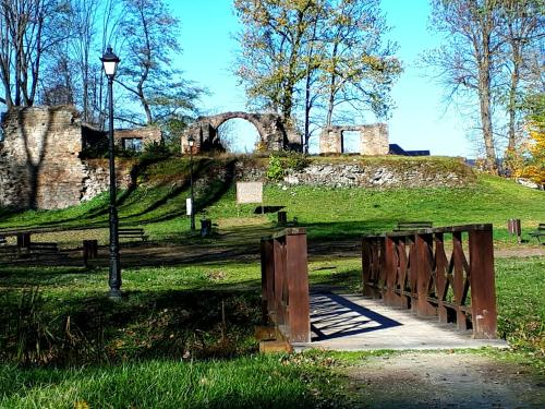 a wooden gate in a park with a building on a hill at Zajazd Podzamcze in Fałków