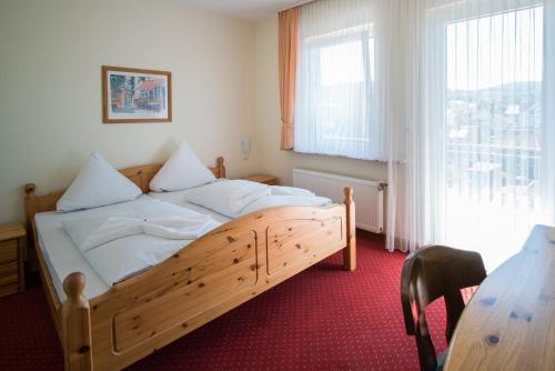 a bedroom with a wooden bed and a table at Hotel-Burghagen in Langelsheim