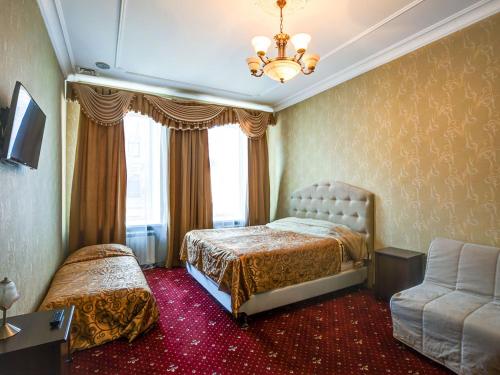 a bedroom with two beds and a chair and a chandelier at Hotel Bolshoy 19 in Saint Petersburg