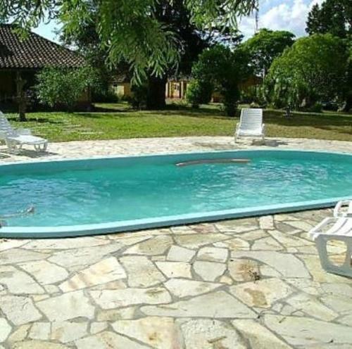 a swimming pool with two lawn chairs at Pousada Chácara das Roseiras in Bagé