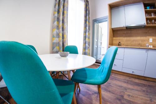 a kitchen with a white table and blue chairs at Central Luxury 1 in Cluj-Napoca