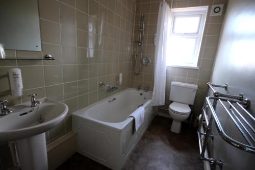 a bathroom with a tub and a toilet and a sink at The Twelve Knights in Port Talbot