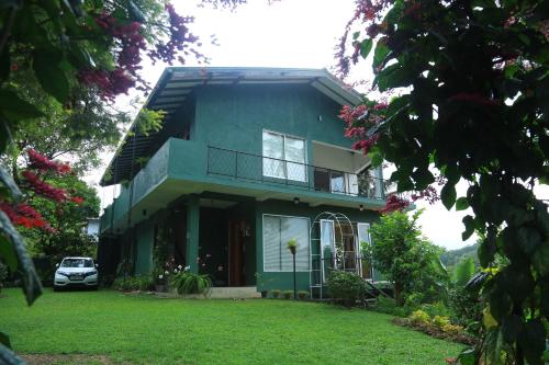 a green house with a car parked in front of it at Riverside Suites in Kandy