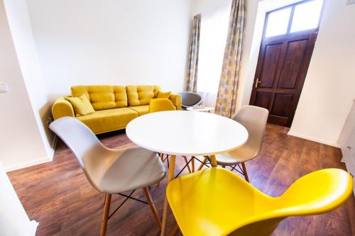 a living room with a yellow couch and a table and chairs at Central Luxury 2 in Cluj-Napoca