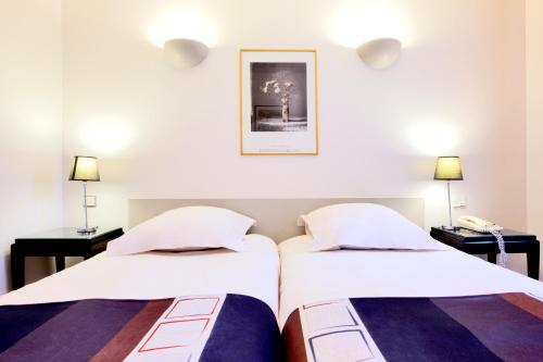 2 Betten in einem Zimmer mit 2 Lampen und einem Telefon in der Unterkunft Kyriad Nimes Centre in Nîmes