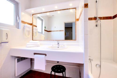 une salle de bain blanche avec un lavabo et un miroir dans l'établissement Kyriad Nimes Centre, à Nîmes