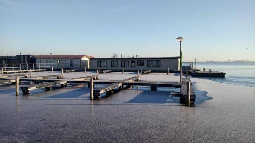 a dock with a building on the water at VISSERSLUST Rooms, Apartments and Houseboats in Vinkeveen
