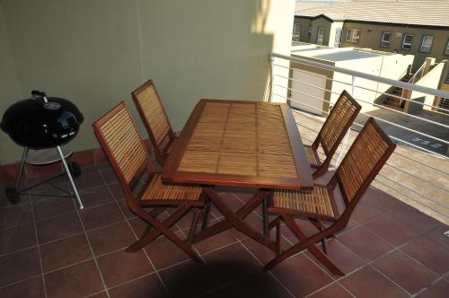 a wooden table and four chairs on a balcony at Bradclin Beach Blouberg in Big Bay