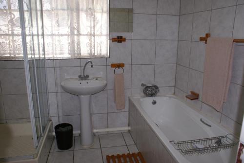 a bathroom with a sink and a bath tub and a sink at Airport Inn Bed and Breakfast in Kempton Park