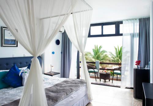 a bedroom with a canopy bed and a balcony at Palmazul Hotel & Spa in San Clemente