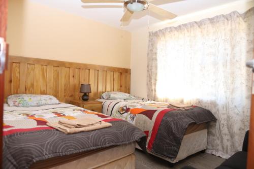 Lodge Huge Dassie في بيلا بيلا: غرفة نوم بسريرين ومروحة سقف