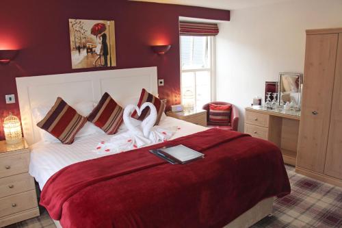 a bedroom with a large bed with a red bedspread at St John's Lodge incl off-site leisure club in Windermere
