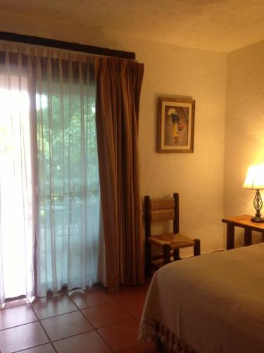 a bedroom with a bed and a window with a chair at Casa d'Lobo Hotel Boutique in Malinalco