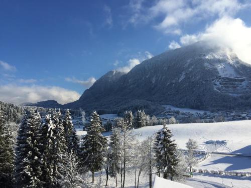 a snow covered mountain with a town and trees at Vivea Gesundheitshotel Bad Häring in Bad Häring