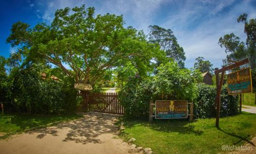 a gate with a sign in front of a tree at Pousada Watu Kerere in Praia do Rosa