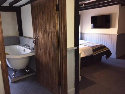 a bathroom with a sink and a tub and a bed at The White Hart in Newenden