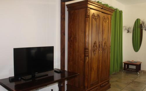 a living room with a television and a large wooden cabinet at Stephna Residence in Anse Boileau