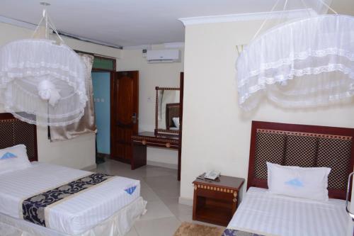a hotel room with two beds and a mirror at Kilimanjaro inn Kampala in Kampala