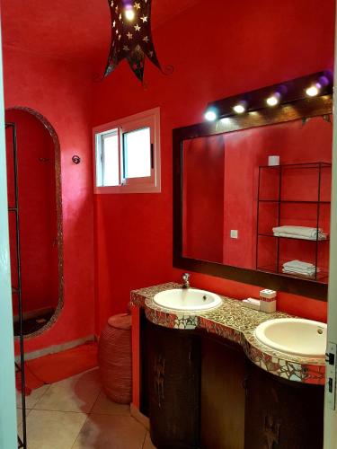 a red bathroom with two sinks and a large mirror at Safari Village Saly V 225 in Saly Portudal