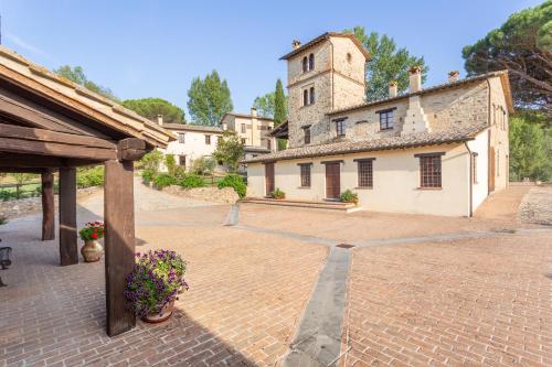 a large brick courtyard with a building with a tower at GH Borgo Pulciano Agriturismo in Montone