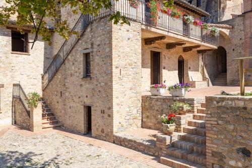a stone building with stairs and potted plants at GH Borgo Pulciano Agriturismo in Montone