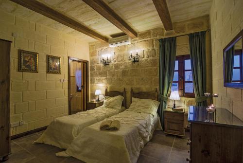 a bedroom with two beds and two tables and two lamps at Blueberry Hills in Żejtun