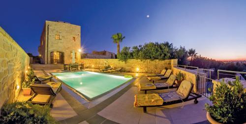 a swimming pool with lounge chairs and a building at Blueberry Hills in Żejtun