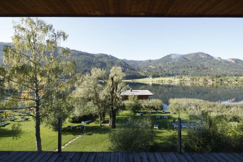 a view of a lake and mountains from a deck at Seehotel Enzian in Weissensee