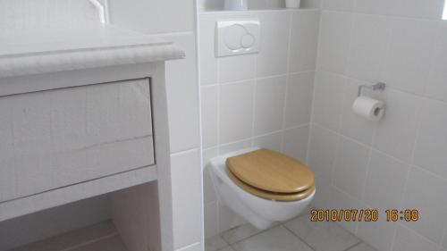 a bathroom with a toilet with a wooden toilet seat at The Tides 7 in Struisbaai