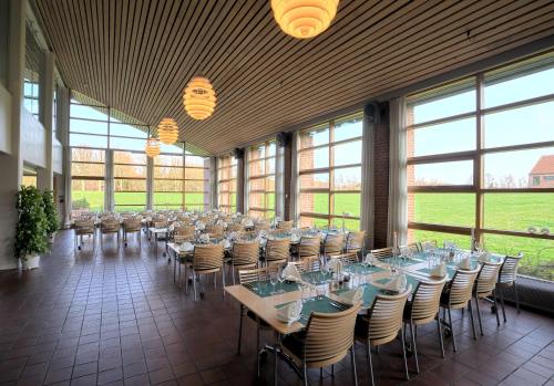 a large room with tables and chairs and windows at Bymose Hegn Hotel & Kursuscenter in Helsinge