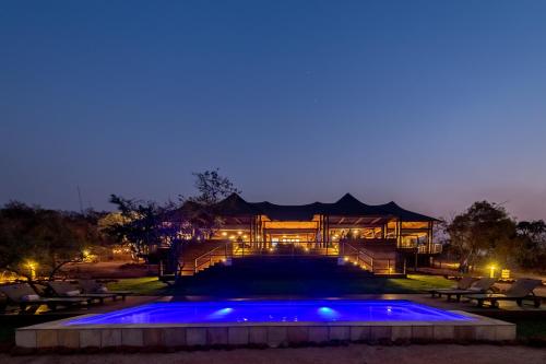 une maison avec piscine la nuit dans l'établissement Ndhula Luxury Tented Lodge, à White River