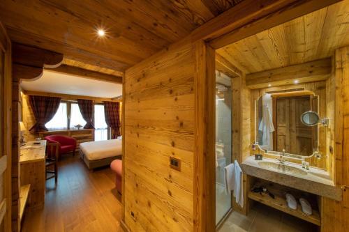 a log cabin bathroom with a sink and a bedroom at Gran Baita Hotel & Wellness in Courmayeur