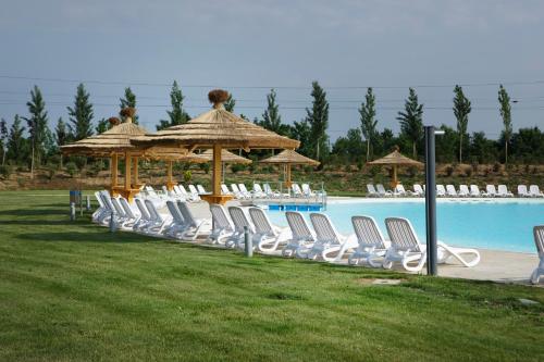 a group of chairs and umbrellas next to a pool at Mjus Resort & Thermal Park in Körmend