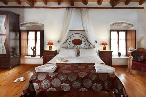 a bedroom with a large bed and two windows at Pietra Suite in Monemvasia