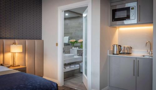 Habitación de hotel con baño con cama y lavamanos en Castletroy Park Hotel Suites, en Limerick