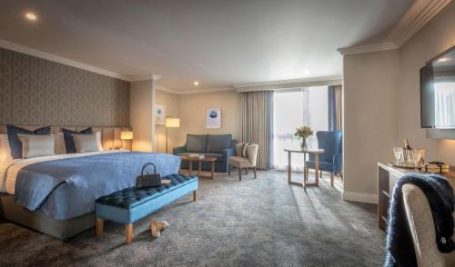 a hotel room with a bed and a couch and chairs at Castletroy Park Hotel Suites in Limerick