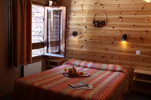 a bedroom with a bed with a tray of fruit on it at Hotel Le Chamois Logis in Molines-en-Queyras