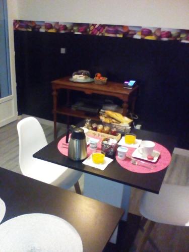 a table with food on top of it with chairs at Chambre d'Hôtes Les Macarons de Tata in Sainte-Eulalie
