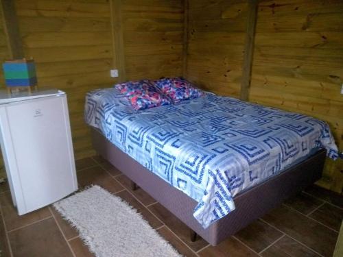 a small bed in a room with a refrigerator at Cabanas do Lorde in Praia do Rosa