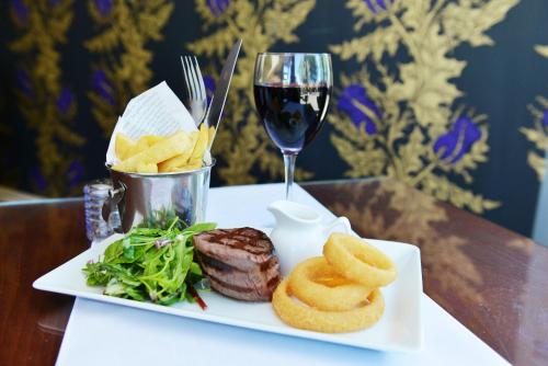 a white plate with food and a glass of wine at Glynhill Hotel & Spa near Glasgow Airport in Paisley