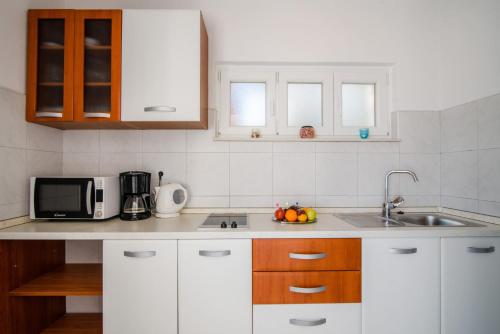 a kitchen with white cabinets and a sink and a microwave at La Bodega Apartments in Trogir
