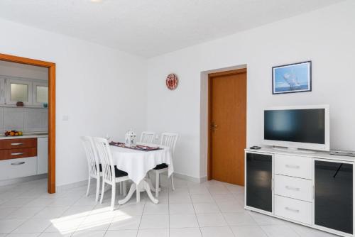 a dining room with a table with chairs and a television at La Bodega Apartments in Trogir