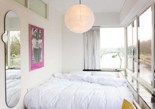a white bedroom with a bed and a large window at SWEETS - Gerben Wagenaarbrug in Amsterdam