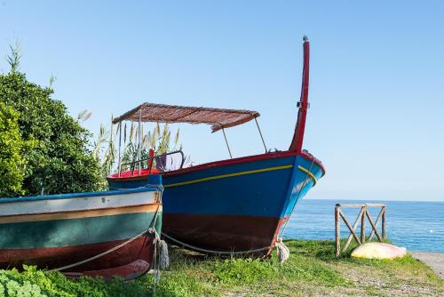 two boats sitting on the grass next to the ocean at Casa del Riccio in Mazzeo