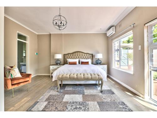 a bedroom with a bed and a chair and a window at The Good Host in Hout Bay
