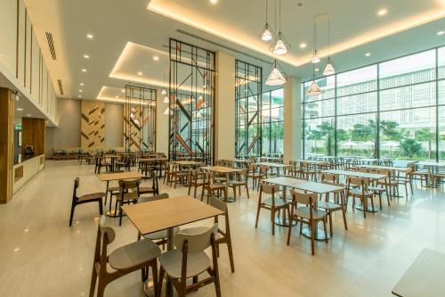 a restaurant with tables and chairs and windows at Paragon Grand Resort in Jomtien Beach