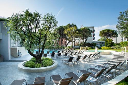 une rangée de chaises et un arbre sur une terrasse dans l'établissement Residence Serenissima, à Bibione