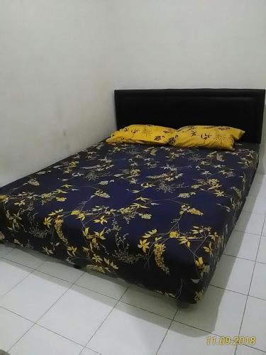 een bed met een zwarte en gele deken en kussens bij Janti Transit Room Syariah in Yogyakarta