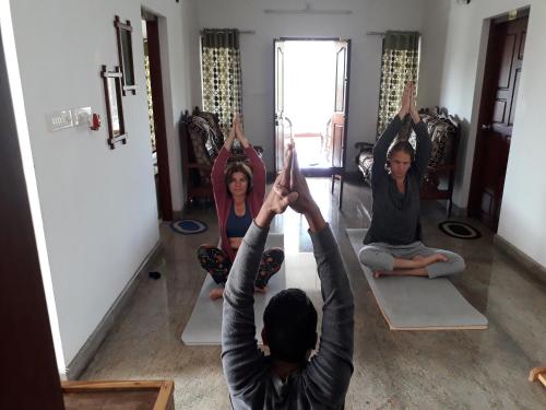 a group of people doing yoga in a room at Mango Kerala Homes in Kumarakom